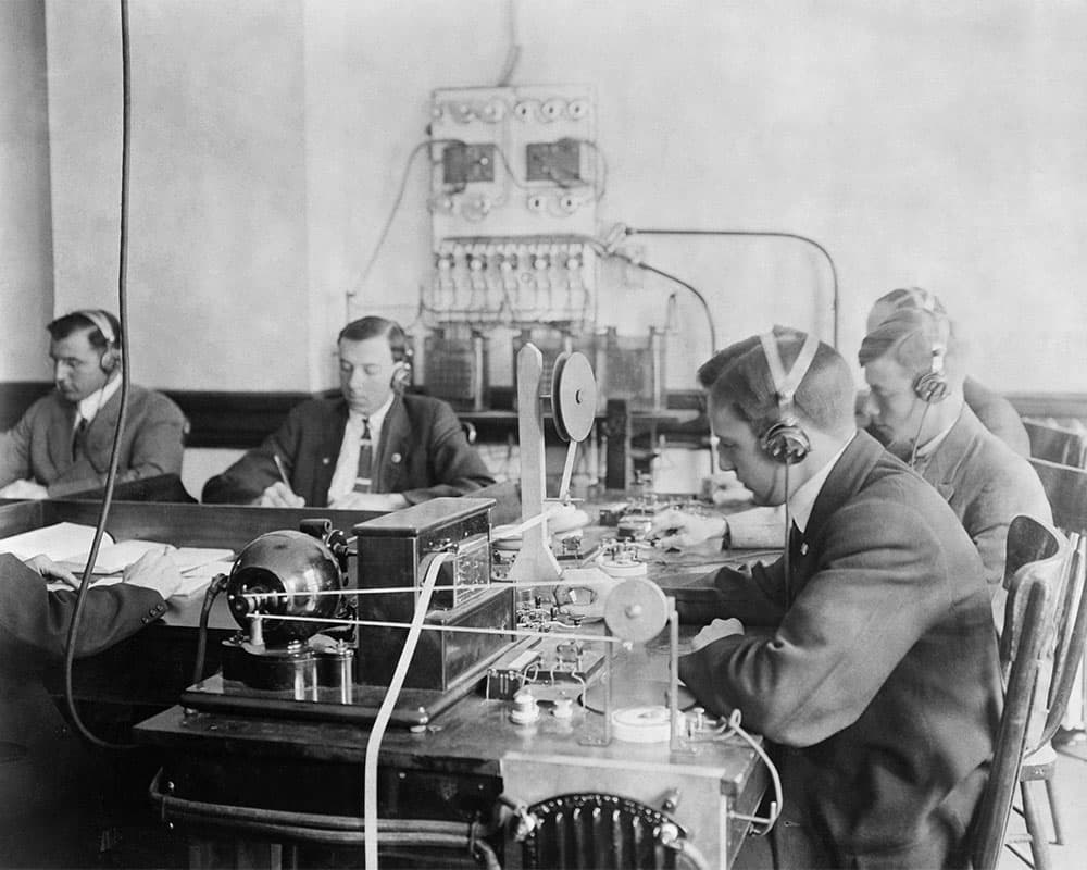 Five men around a table copying down telegraph messages