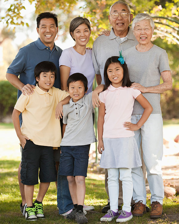 Three generations of a family stand and smile together.