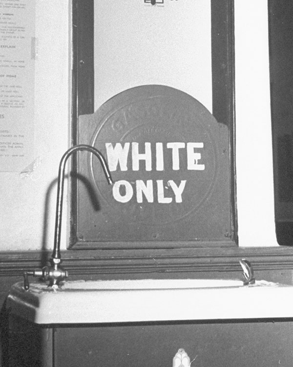 A sign at a water fountain says white only