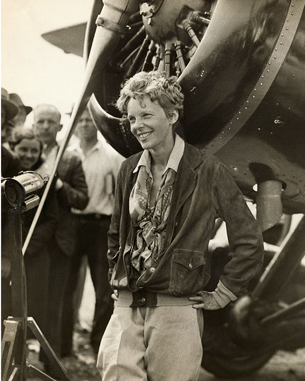 Amelia Earhart smiles near her plane’s propeller