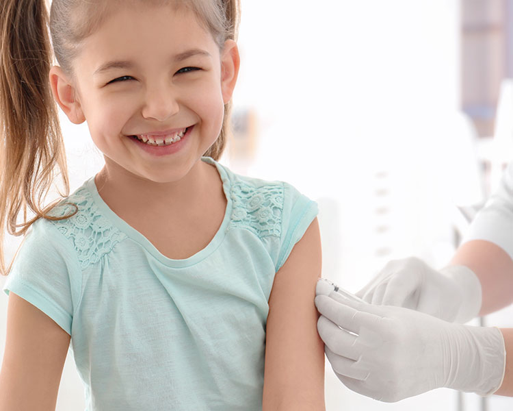 A young girl smiles while receiving a vaccine shot