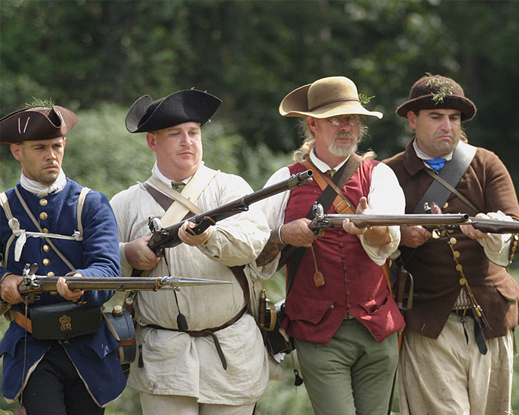 Soldiers march with their muskets aimed forward