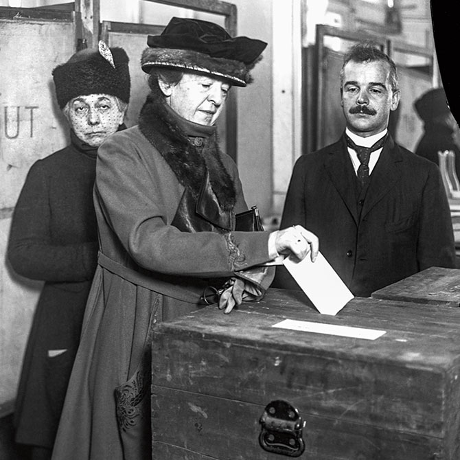 A woman casts her vote into a ballot box