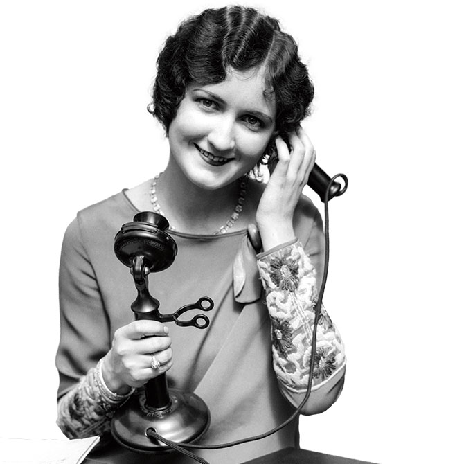 A woman listens on an old phone.
