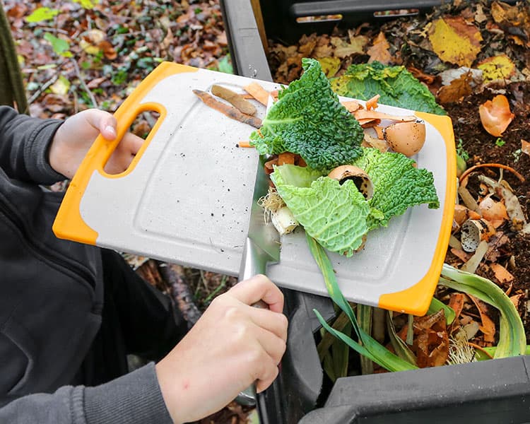 Person scraping food scraps into a compost bin