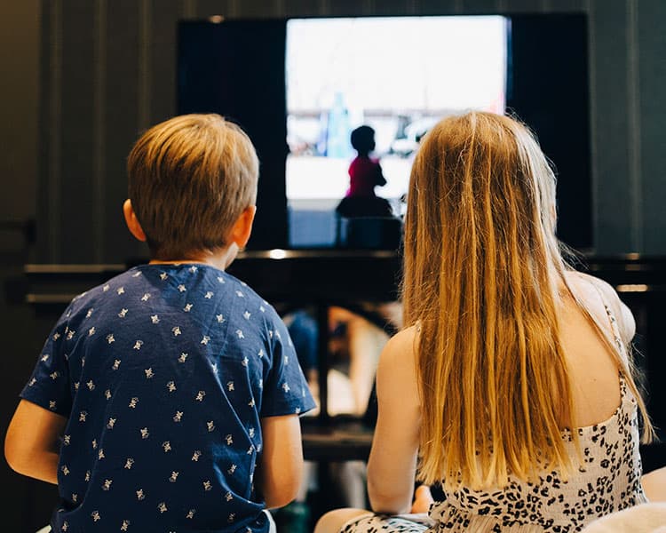 two children playing video games, seen from the back