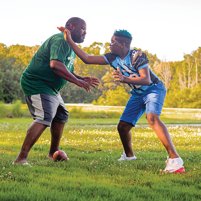 Enlargeable photo of Isaiah working on a football drill with his father