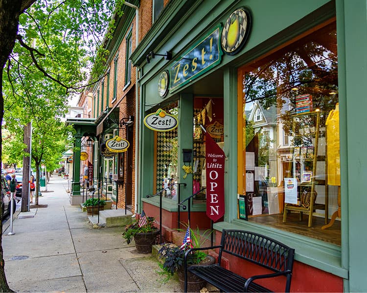 a quaint tree-lined main street with shops and benches