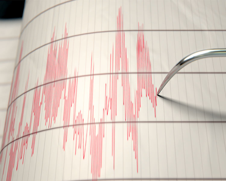 A tool writing red lines going up and down on a paper as it measures the strength of earthquake