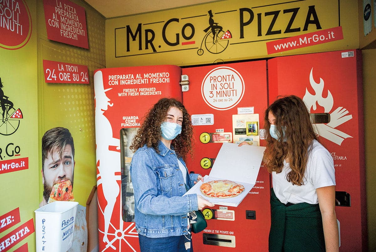 Customers holding a pizza.