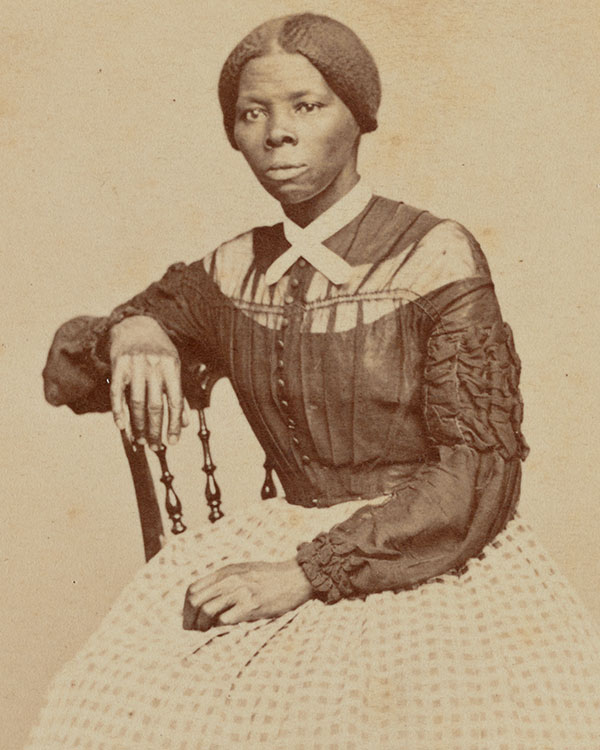 Black and white photo of a stern looking woman sitting as she poses for the photo