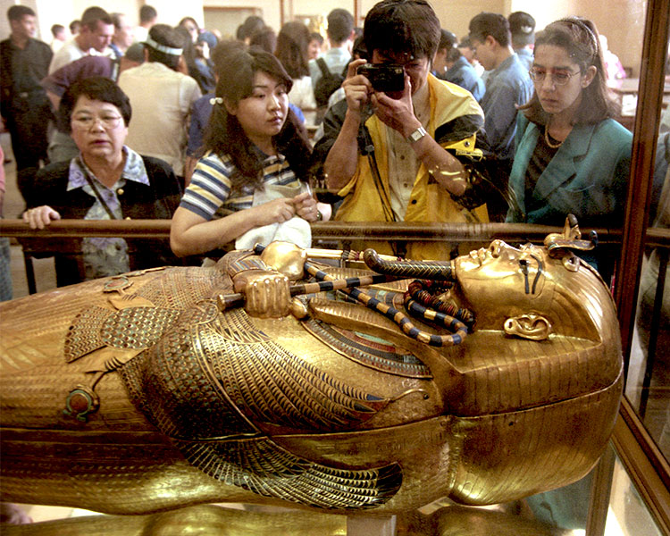 People in a museum looking at a mummy&apos;s coffin