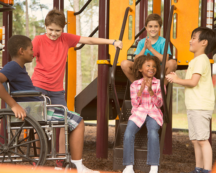 Children playing and talking with a child in a wheelchair at the playground