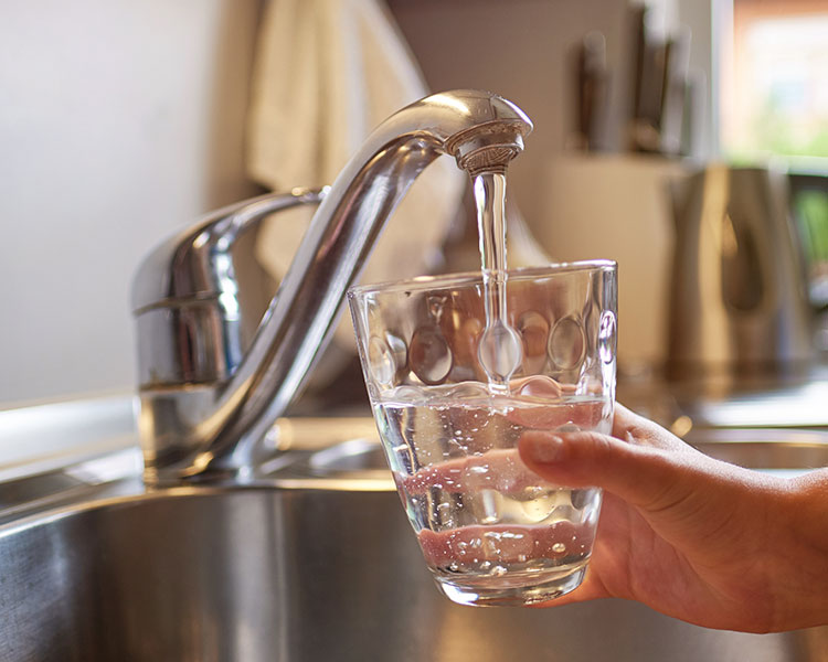 Someone filling a glass with water from the sink