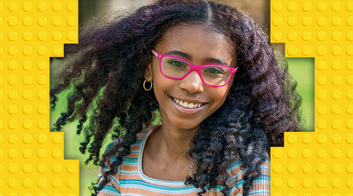 A girl with long curly unbraided hair and pink glasses