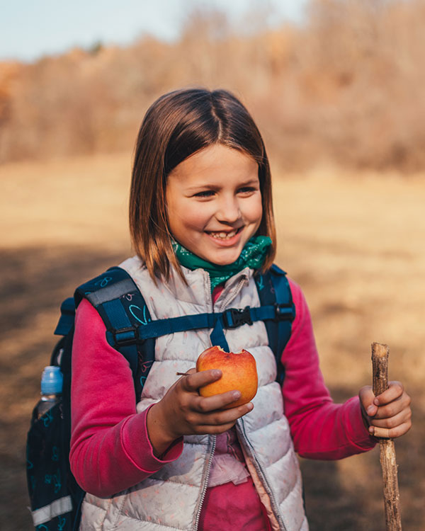 A child taking a break from her hike to eat an apple