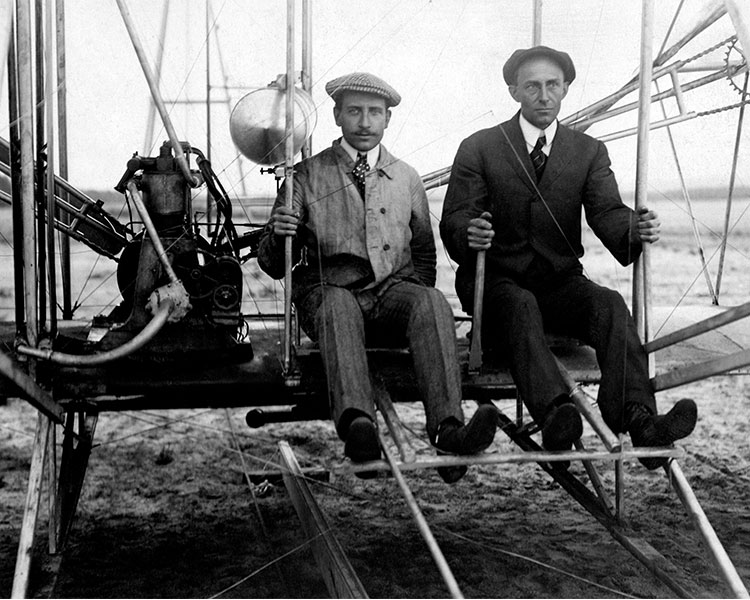Black & white photo of two people sitting on a man-made contraption