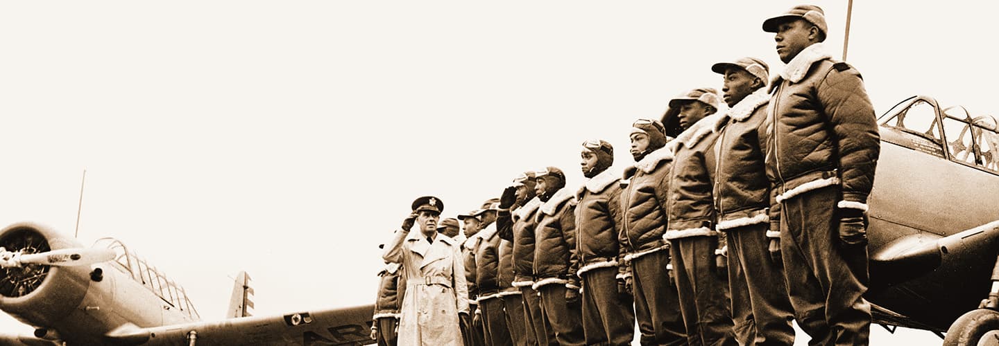 Sepia tone image of air officers posing with planes in the background