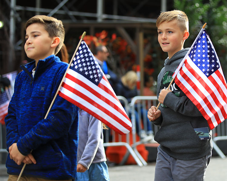 Image of students walking down the street and holding American flags