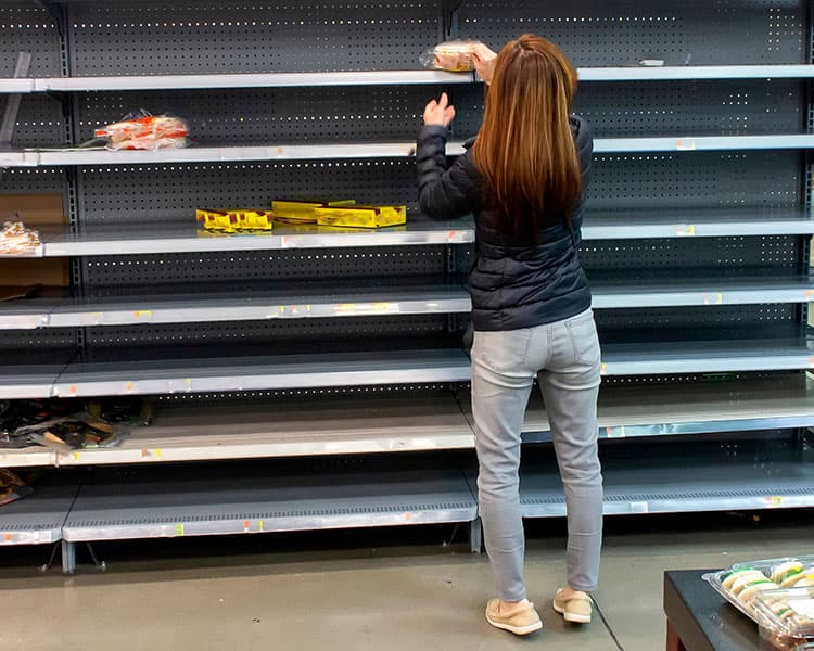 Photo of a person shoppping among nearly empty shelves in a store