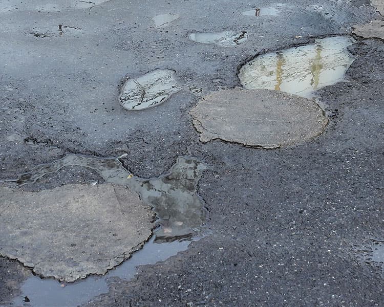 A road full of potholes filled with rainwater