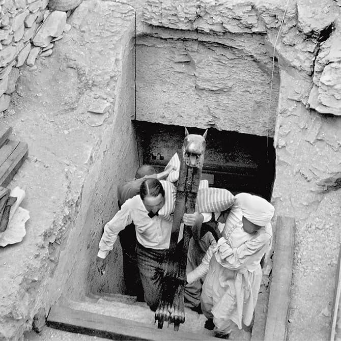 Enlargeable black & white photo of people carrying items out from King Tut&apos;s tomb site