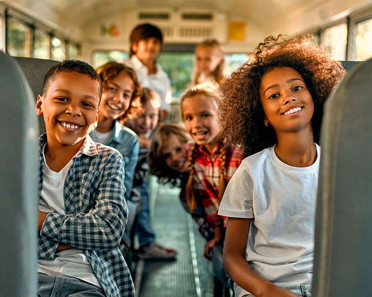 Image of an aisle of a school bus and kids smiling