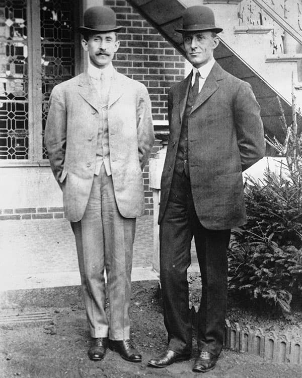 Black & white photo of two men wearing suits and hats