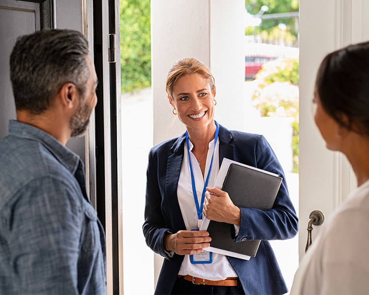 Photo of a representative standing at the door of two citizens