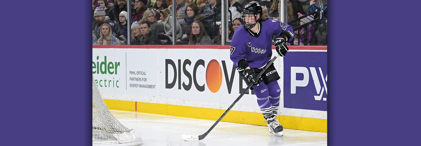 Photo of a hockey player skating on ice while crowd watches