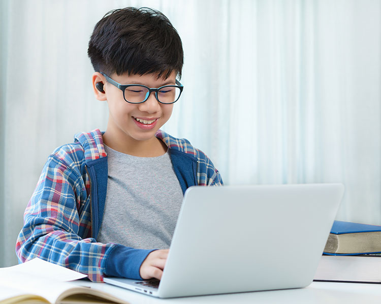 Photo of a student smiling and working on their laptop