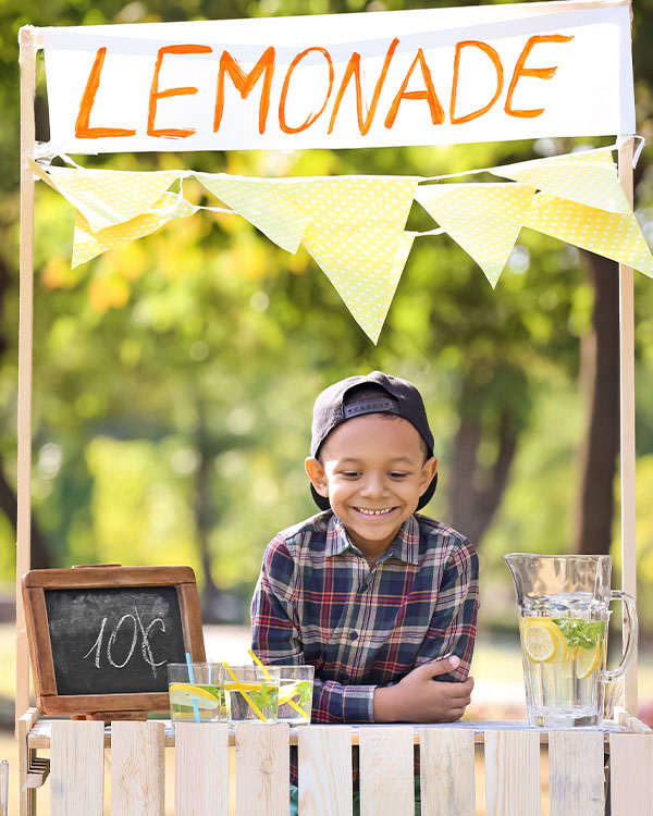 Photo of a smiling student holding a lemonade stand