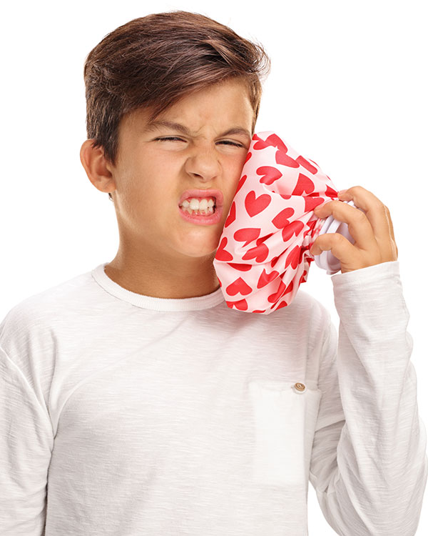 Photo of a kid appearing to be in pain while holding ice bag to cheek