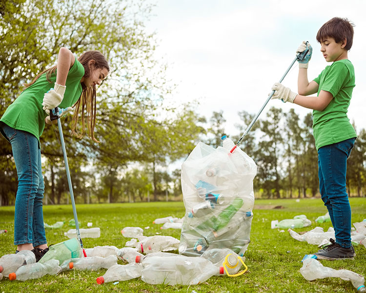 Photo of two kids helping recycle littered bottles