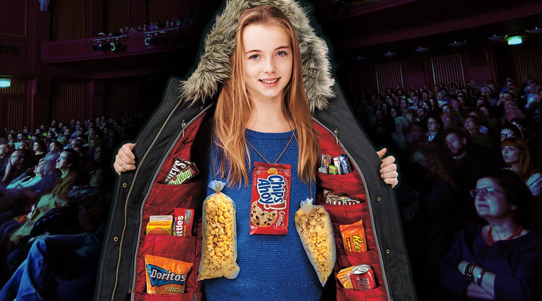 Image of a kid wearing a coat full of snacks in a movie theatre