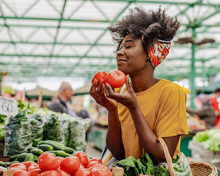 Image of a person in a grocery store picking up fresh tomatoes