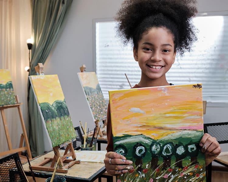 Image of a smiling student with completed painting in hands