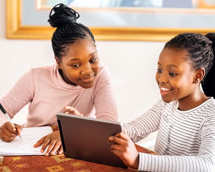 Photo of a student showing another student something on her tablet