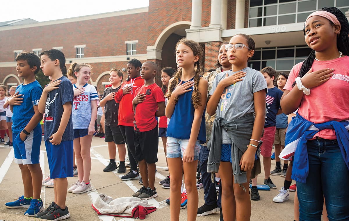 Photo of students gathered outside with their hands over their hearts