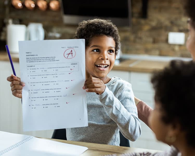 Photo of an excited kid showing a parent the A they earned on their school test