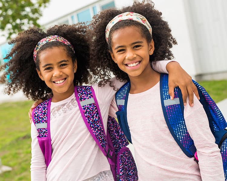 Image of young twins smiling and wearing matching clothes