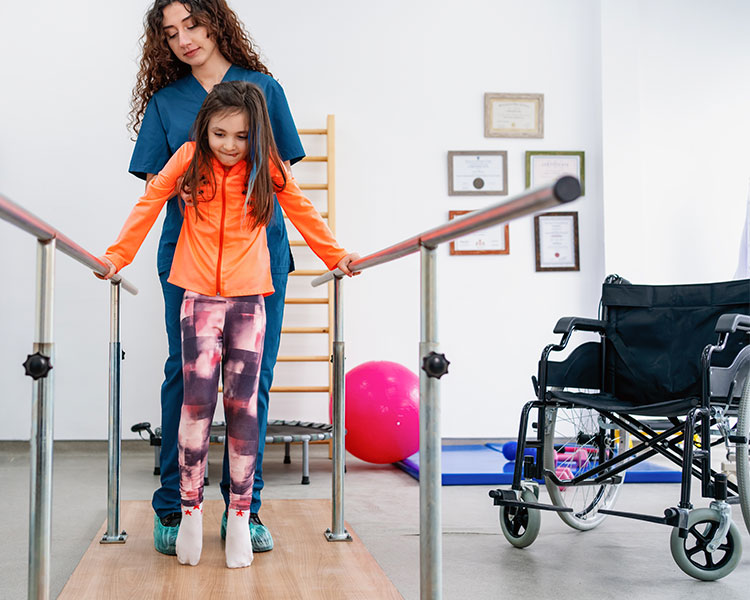 Photo of a physical therapist helping a young girl walk with two bars on either side