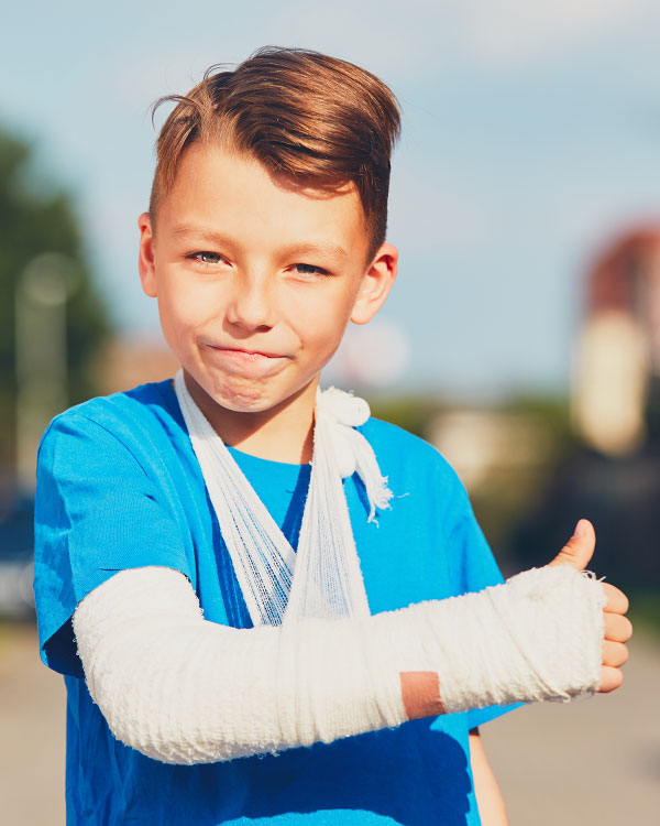 Photo of kid wearing cast on arm and giving thumbs up sign